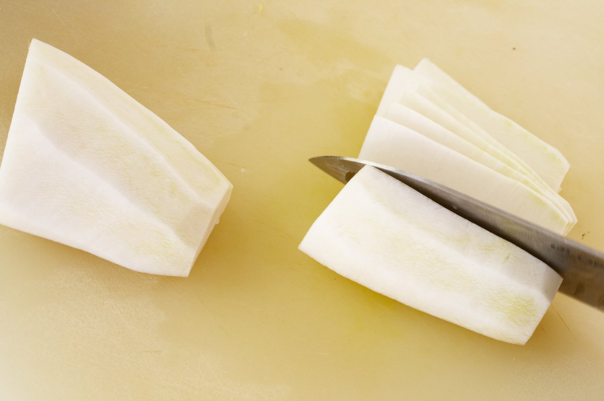 making flat slices for radish kimchi