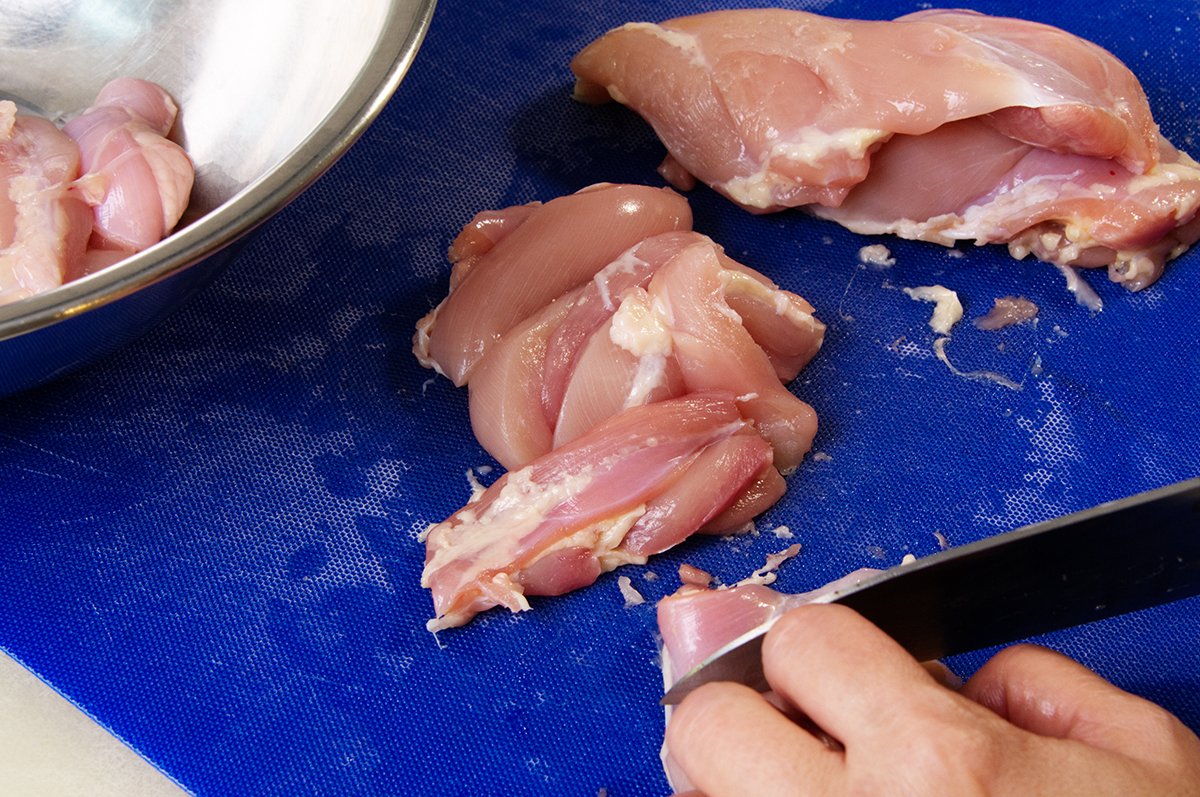 slicing chicken into strips for satay