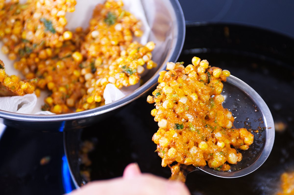 taking out the fried corn fritter of the oil