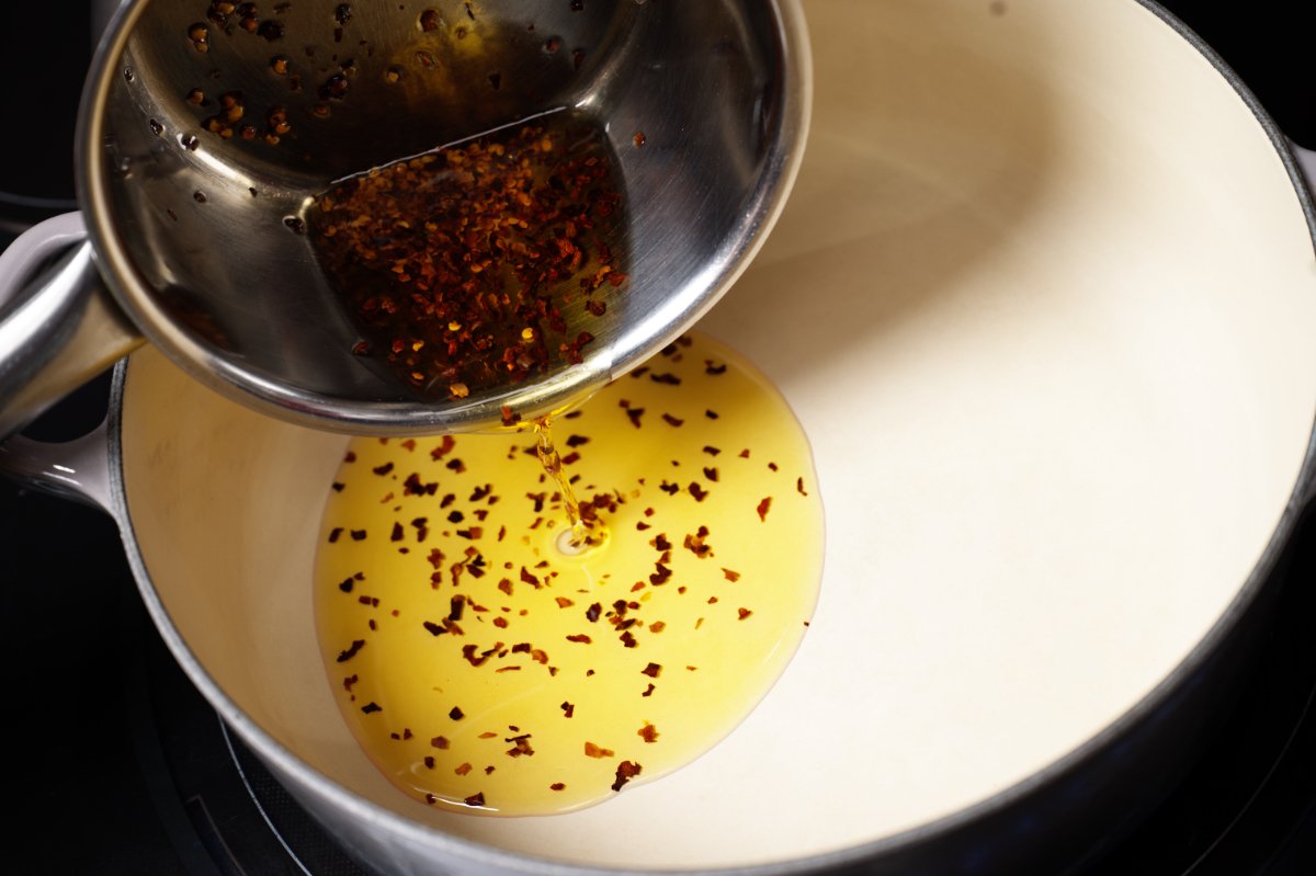 pouring chili oil and chilis into pan