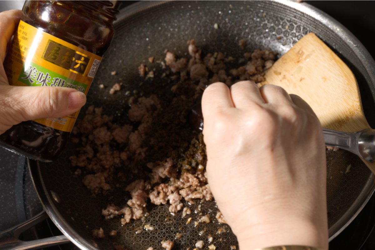 adding sweet bean sauce to dan dan meat