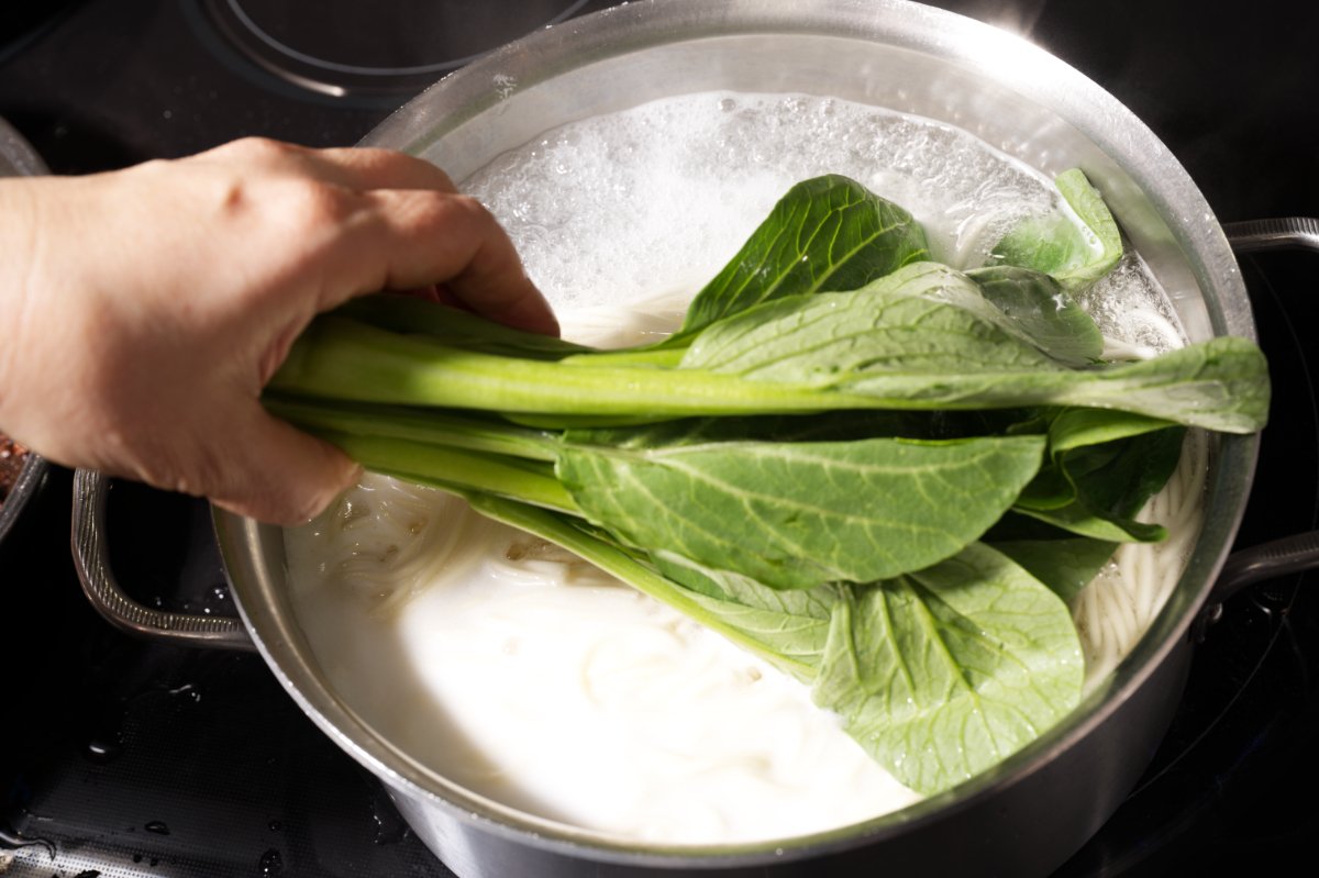 adding the greens to the noodles