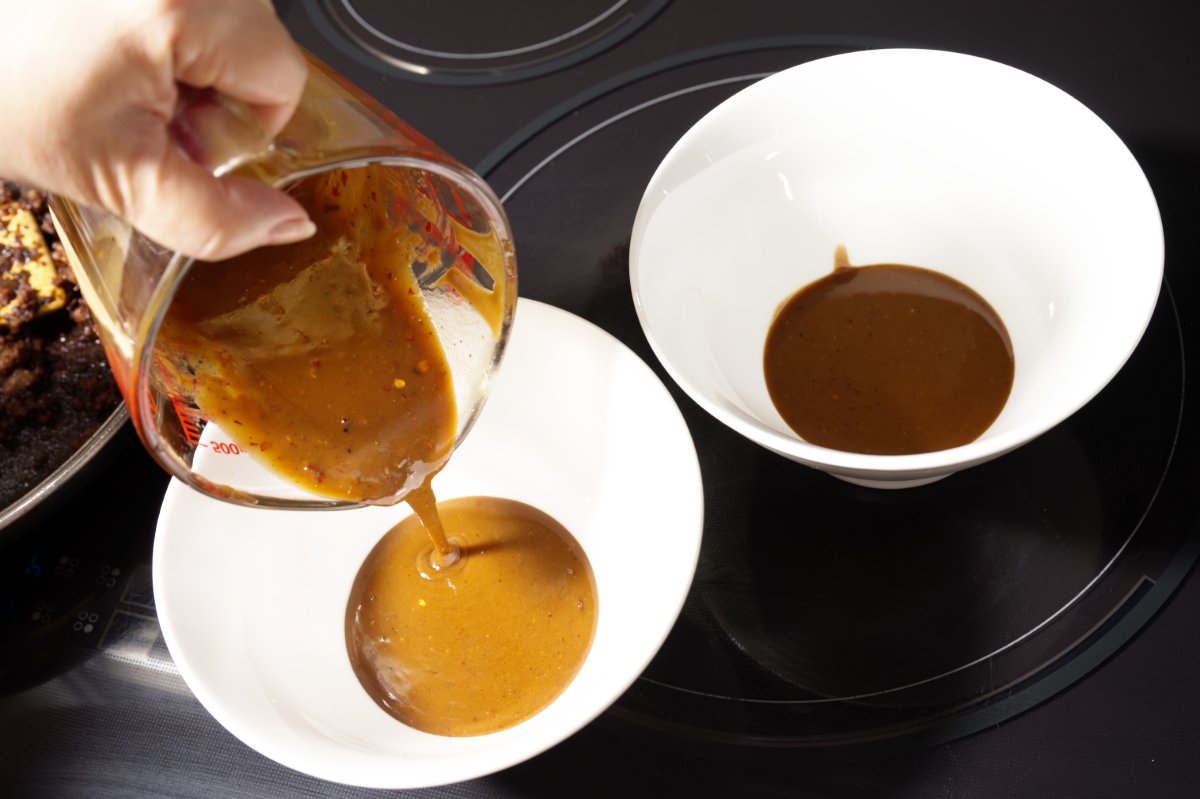 putting the sauce on the bottom of the noodle bowls