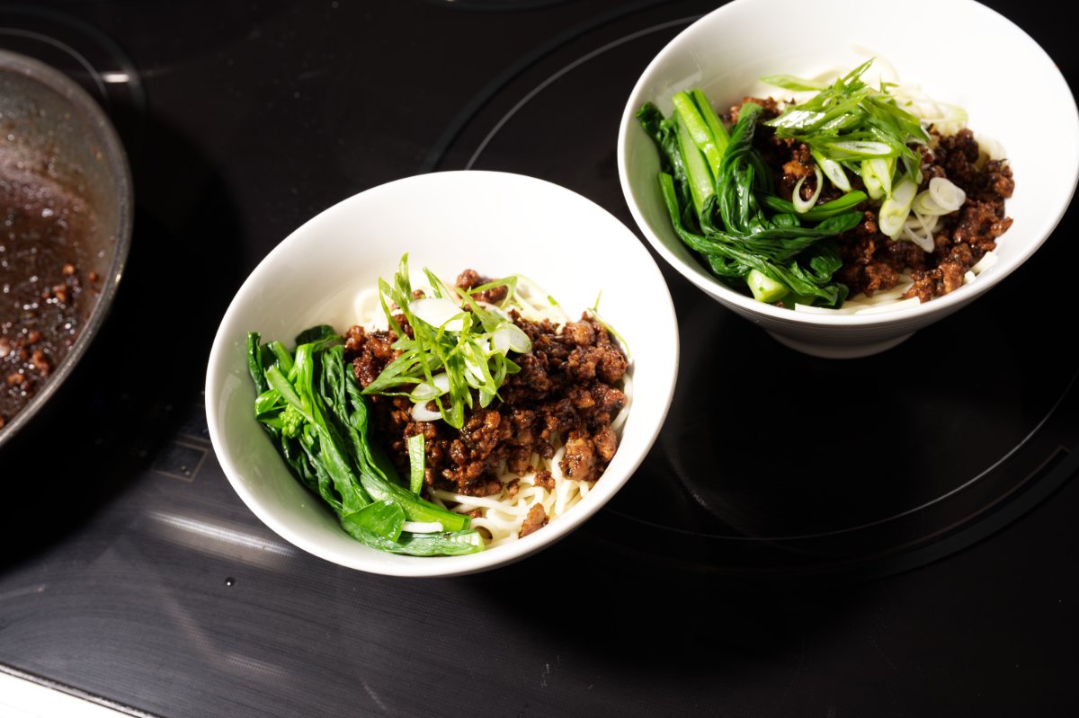 finishing off dan dan noodle bowls with greens and garnish