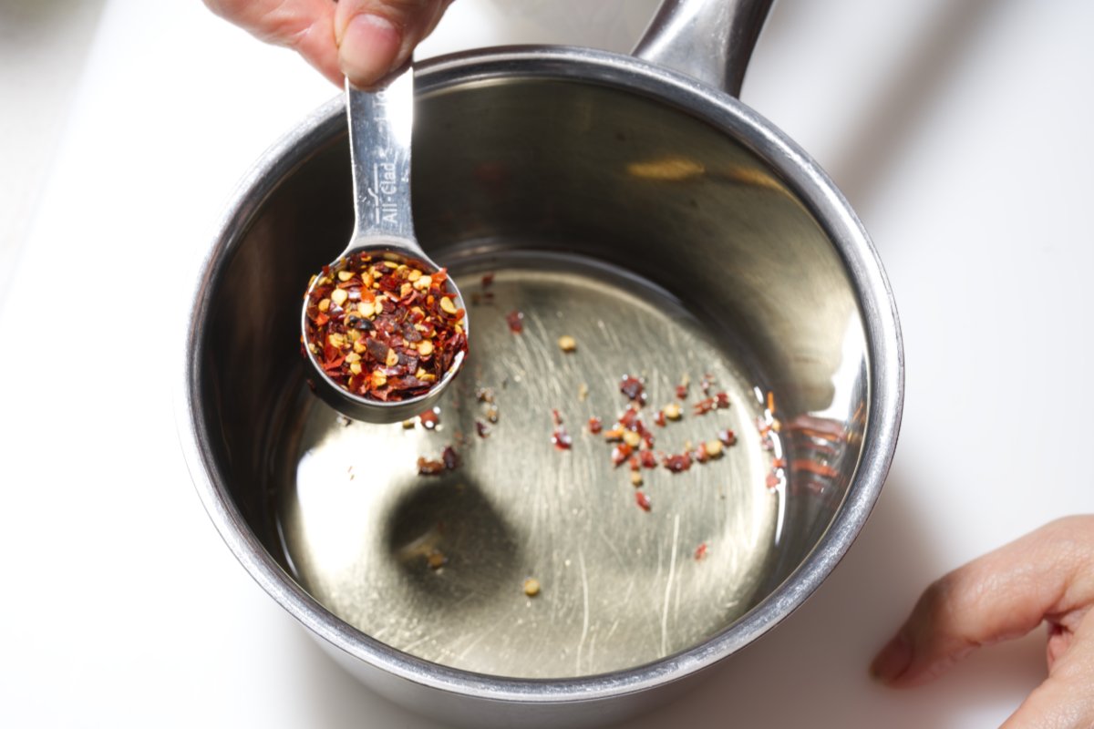adding chili flakes to oil for dan dan noodles