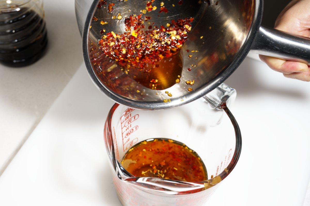 adding the chili oil to dan dan noodles sauce