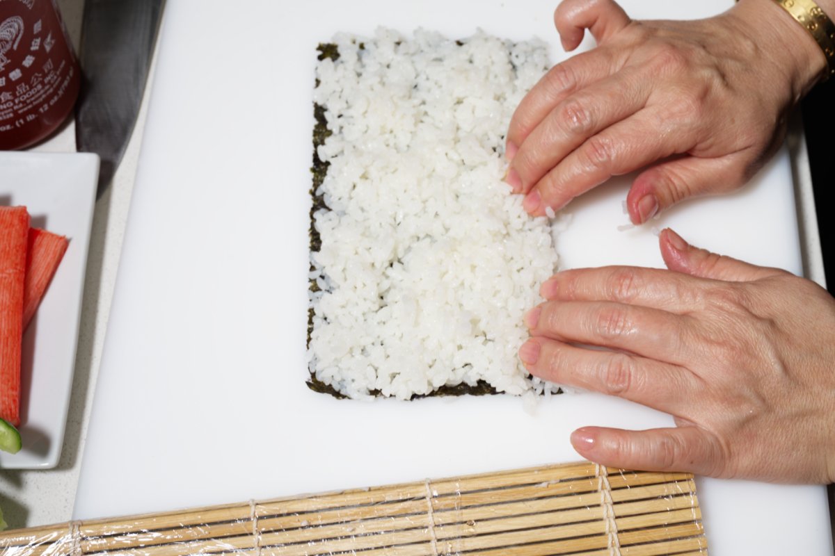 pulling the rice over seaweed california rolls