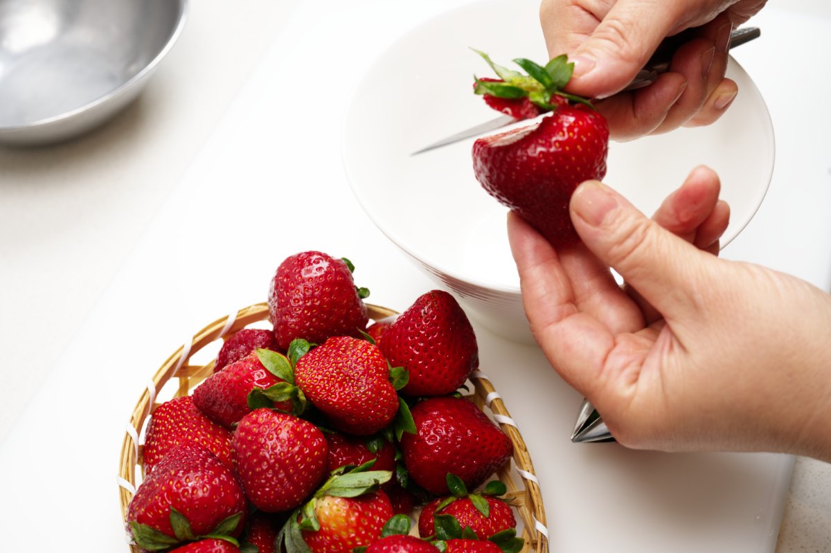 using a knife to remove stem from strawberries