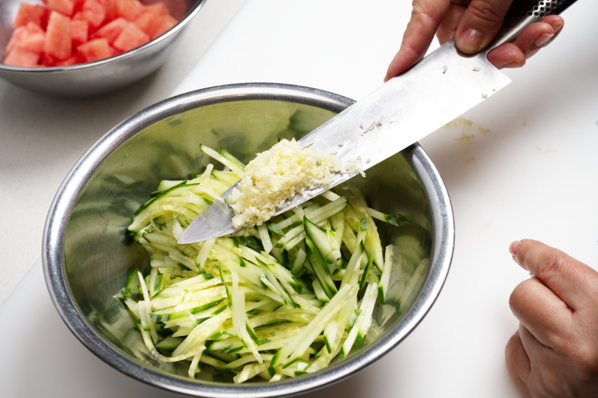 adding garlic and ginger to cucumbers