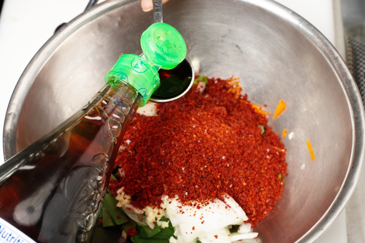adding fish sauce to stuffed cucumber kimchi