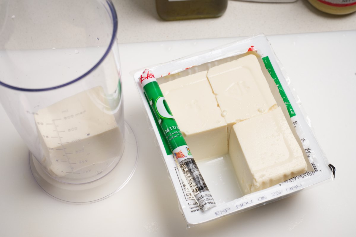 adding silken tofu to container for kale caesar salad