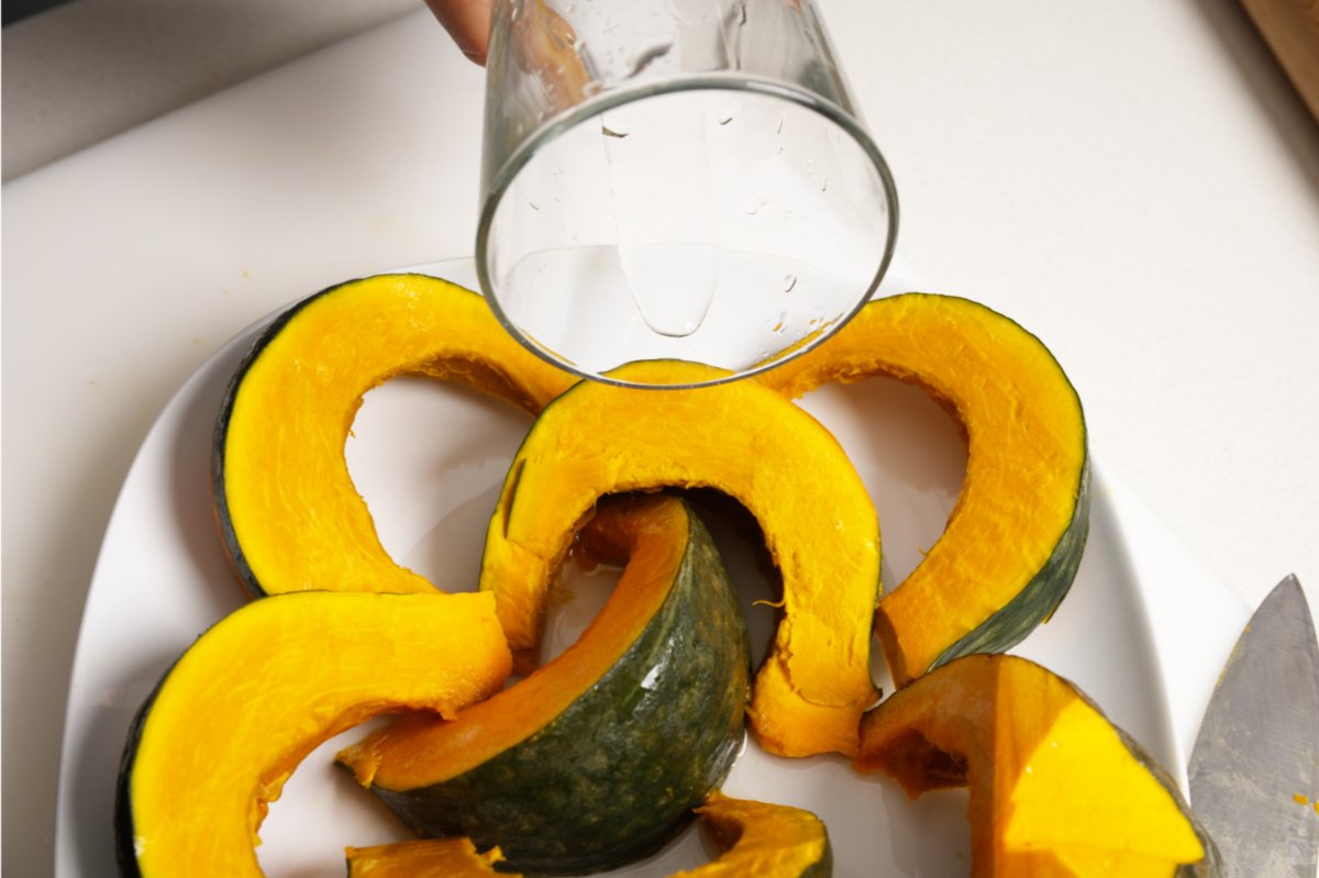 adding water to plate to steam kabocha for salad