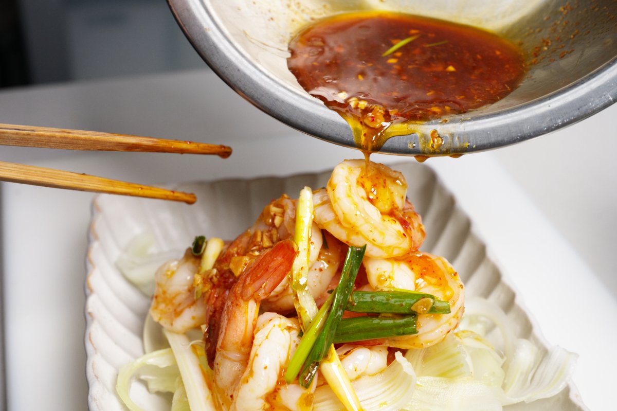 pouring dressing on top of shrimp and celery salad