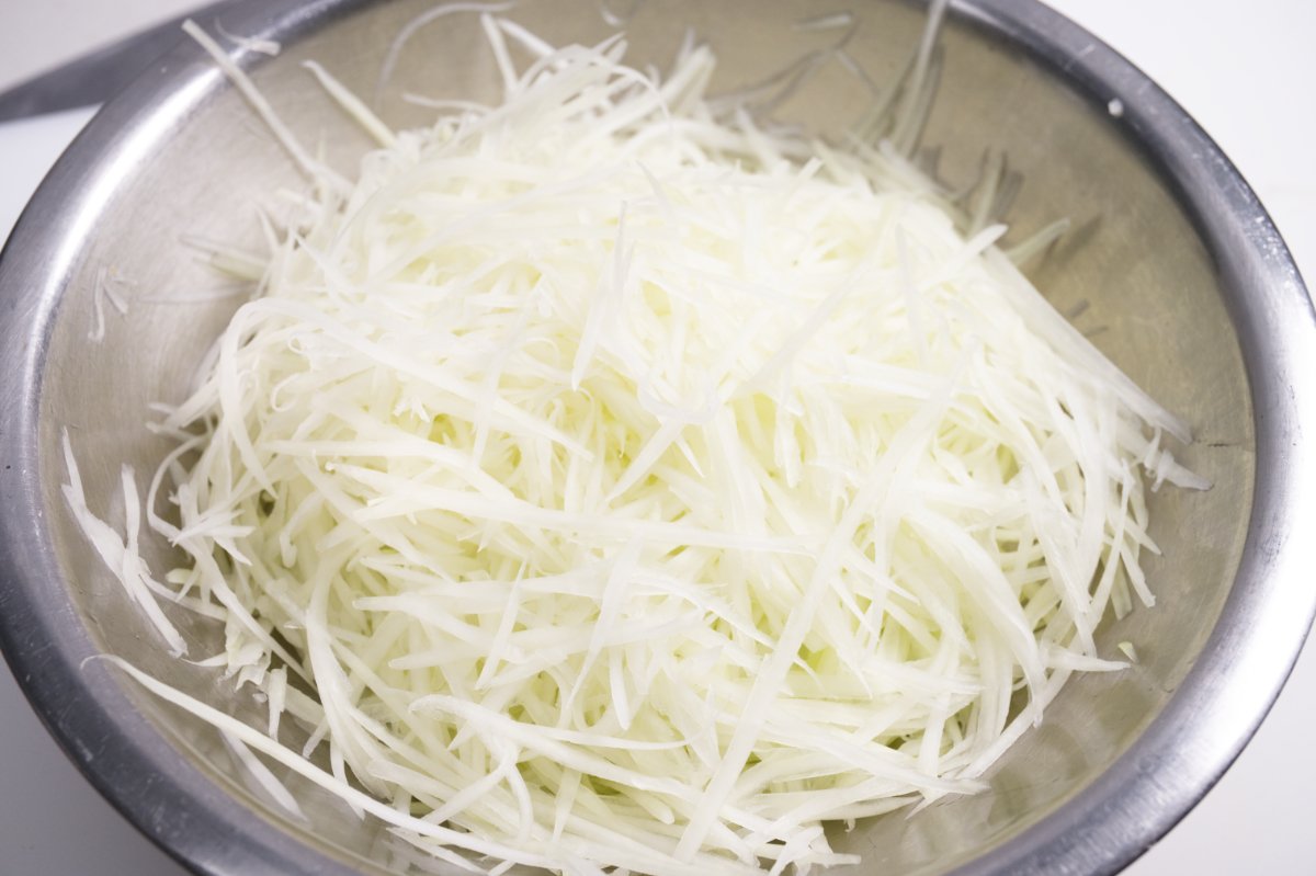 bowl filled with shredded green papaya for slaw