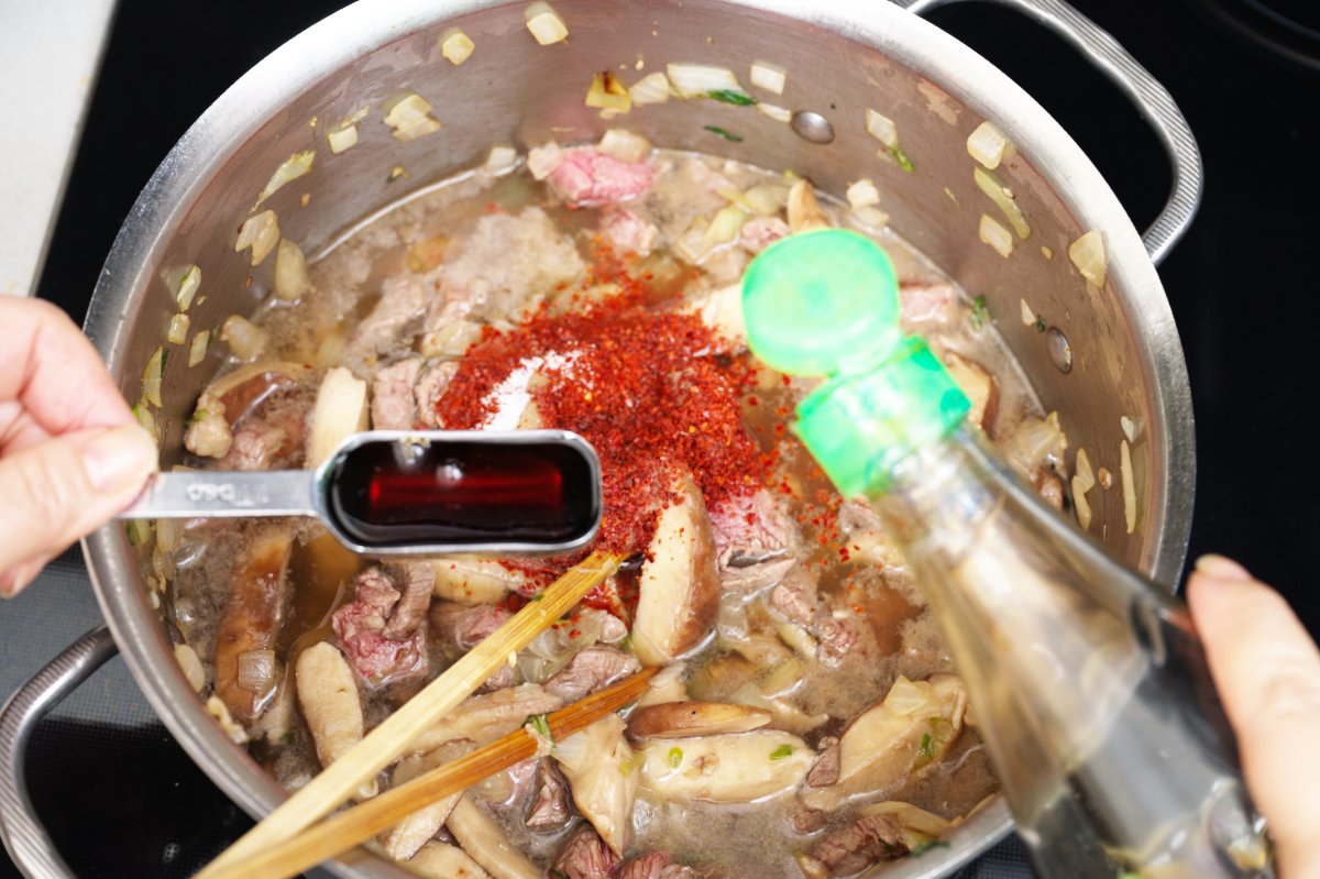 adding fish sauce and sesame oil to beef sundubu-jjigae