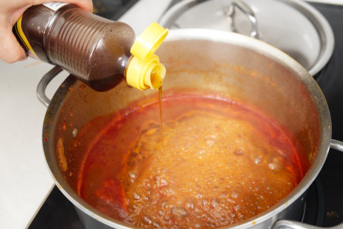 adding sesame oil to the sauce for spicy Korean braised chicken