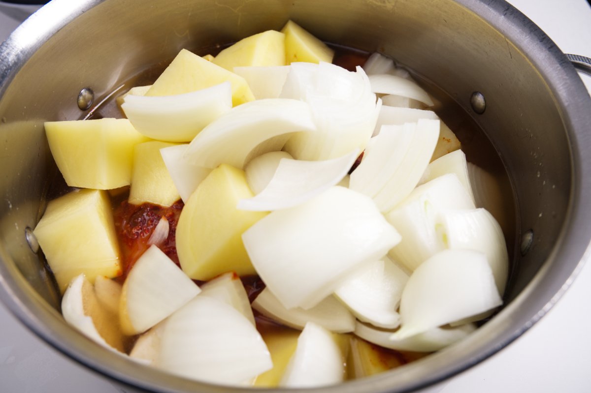adding chicken, potatoes, and onion to dutch oven for spicy Korean braised chicken