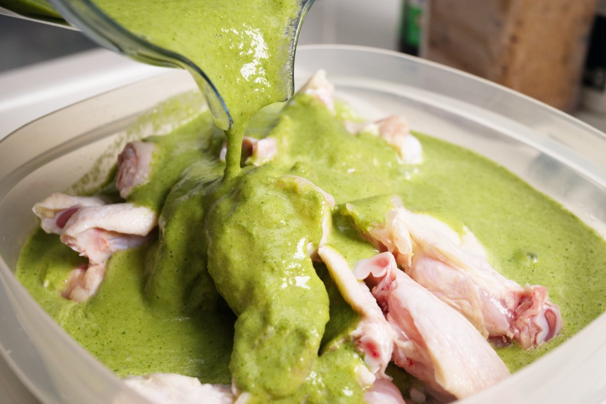 Pouring the green curry wings marinade over chicken